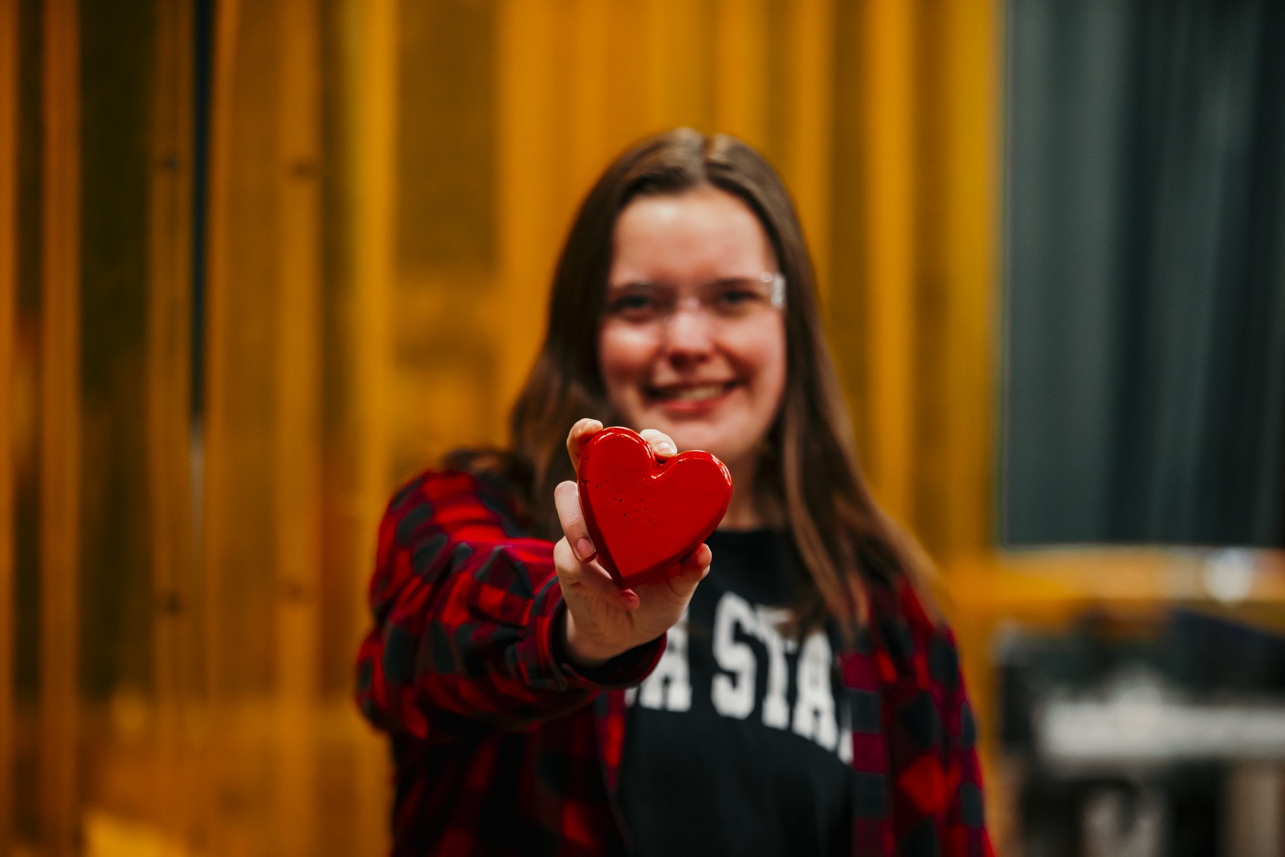 Claire Palmer holding a red concrete heart towards the camera