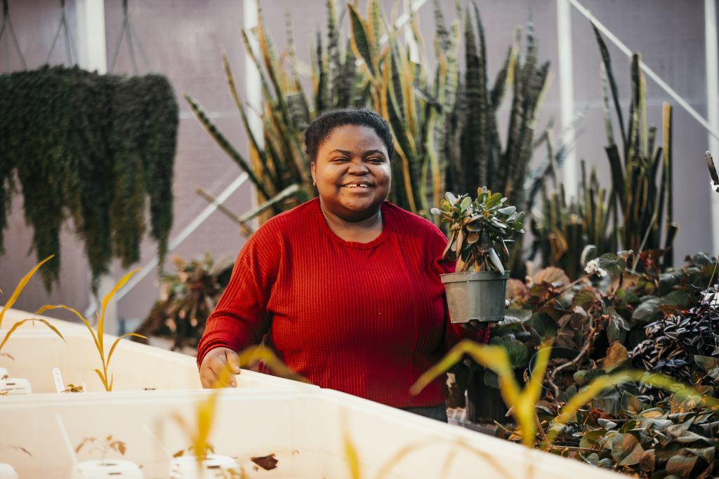 Kafunda in an ISU greenhouse smiling at the camera