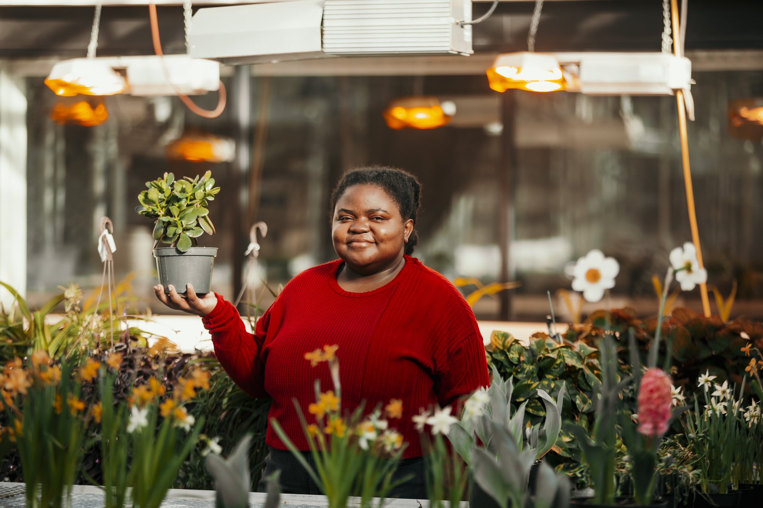 Kafunda in an Iowa State greenhouse holding a house plant