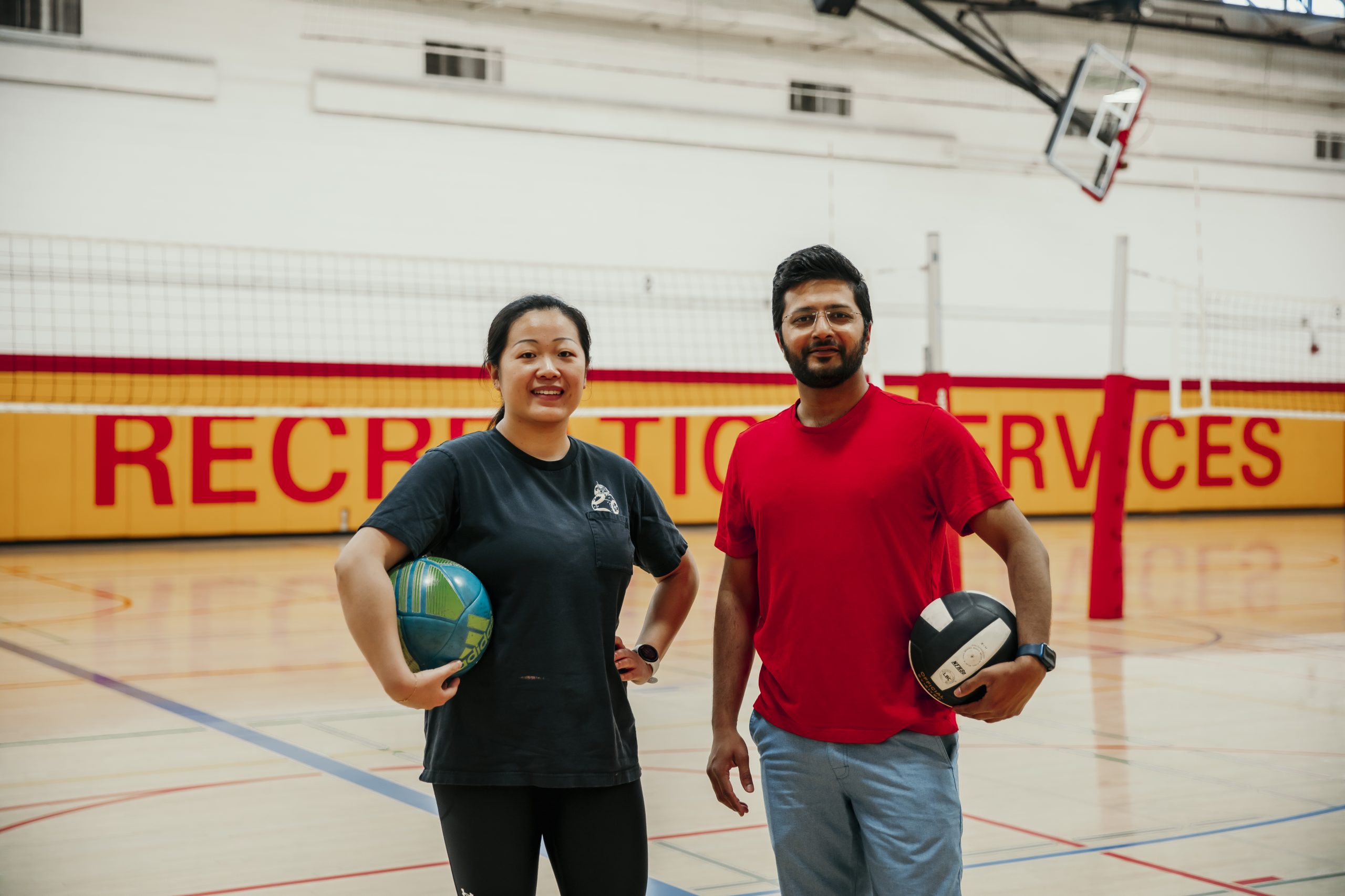 Shoaib Ahmed and Jia Liu holding a ball inside the gymnasium 