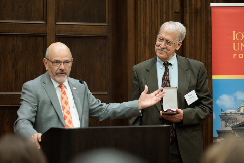 College of Engineering Dean Easterling speaks with professor Doug Jacobson holding the medallion for the Sunil and Sujata Geitonde Professorship in Cybersecurity. 