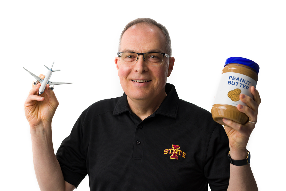 Ted Heindel holds an airplane in one hand and jar of peanut butter in the other hand