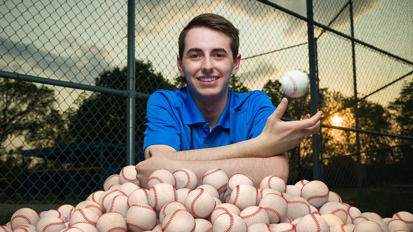 Henry Shires poses behind a pile of baseballs