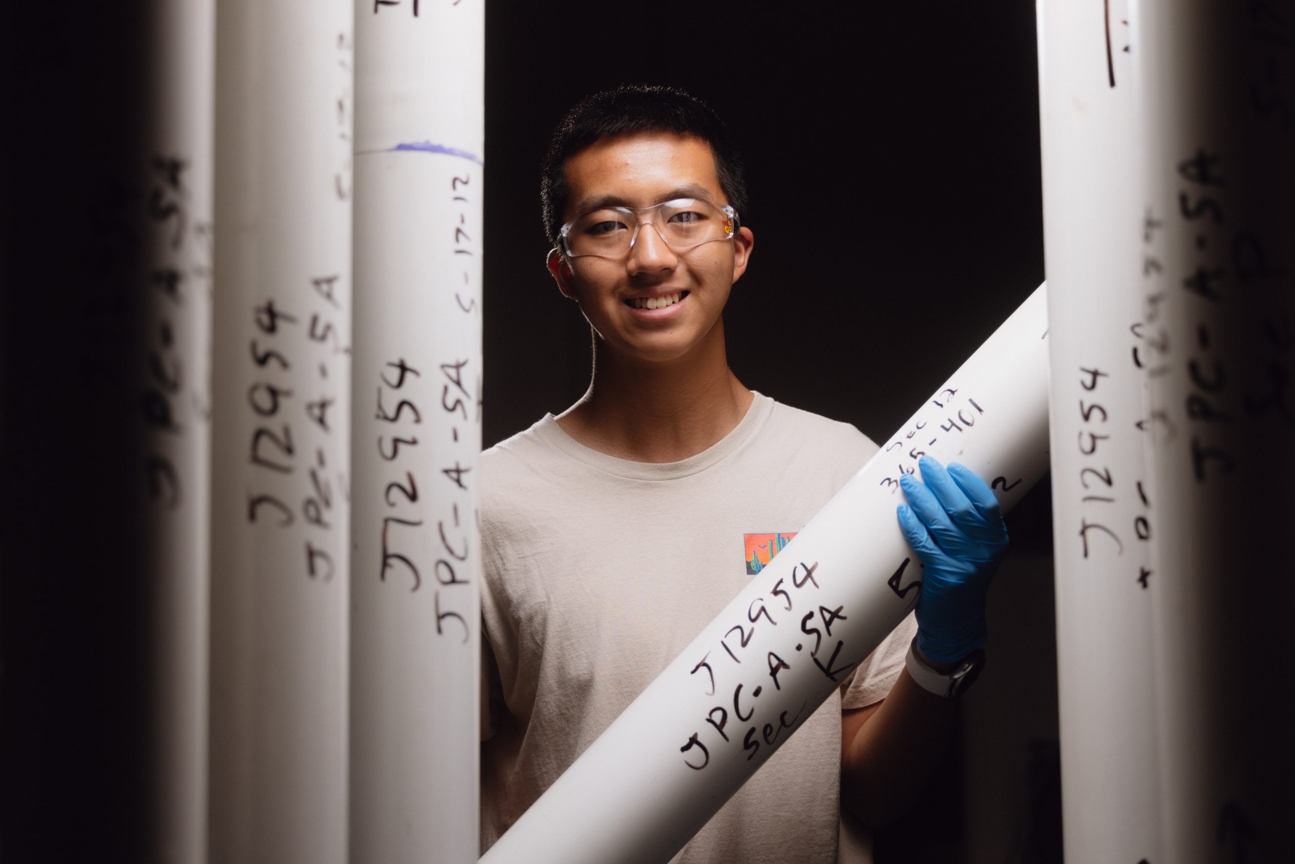 Aidan Lee holds a white cylinder containing soil samples.