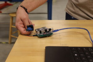 Student holding muon detector attached to laptop computer