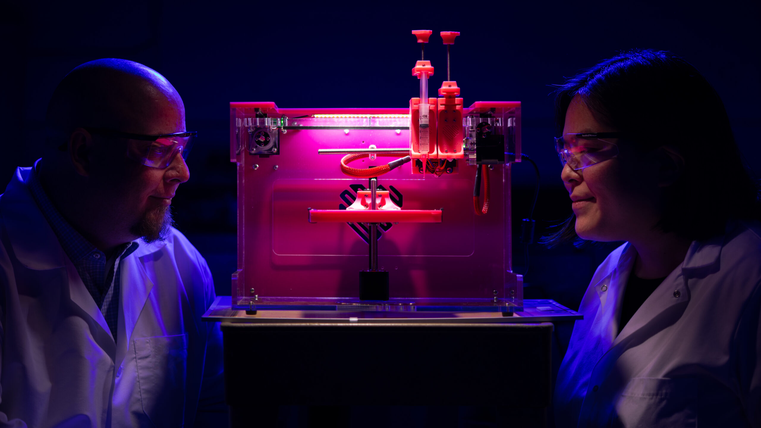Two scientists with bright pink 3D bio-printer