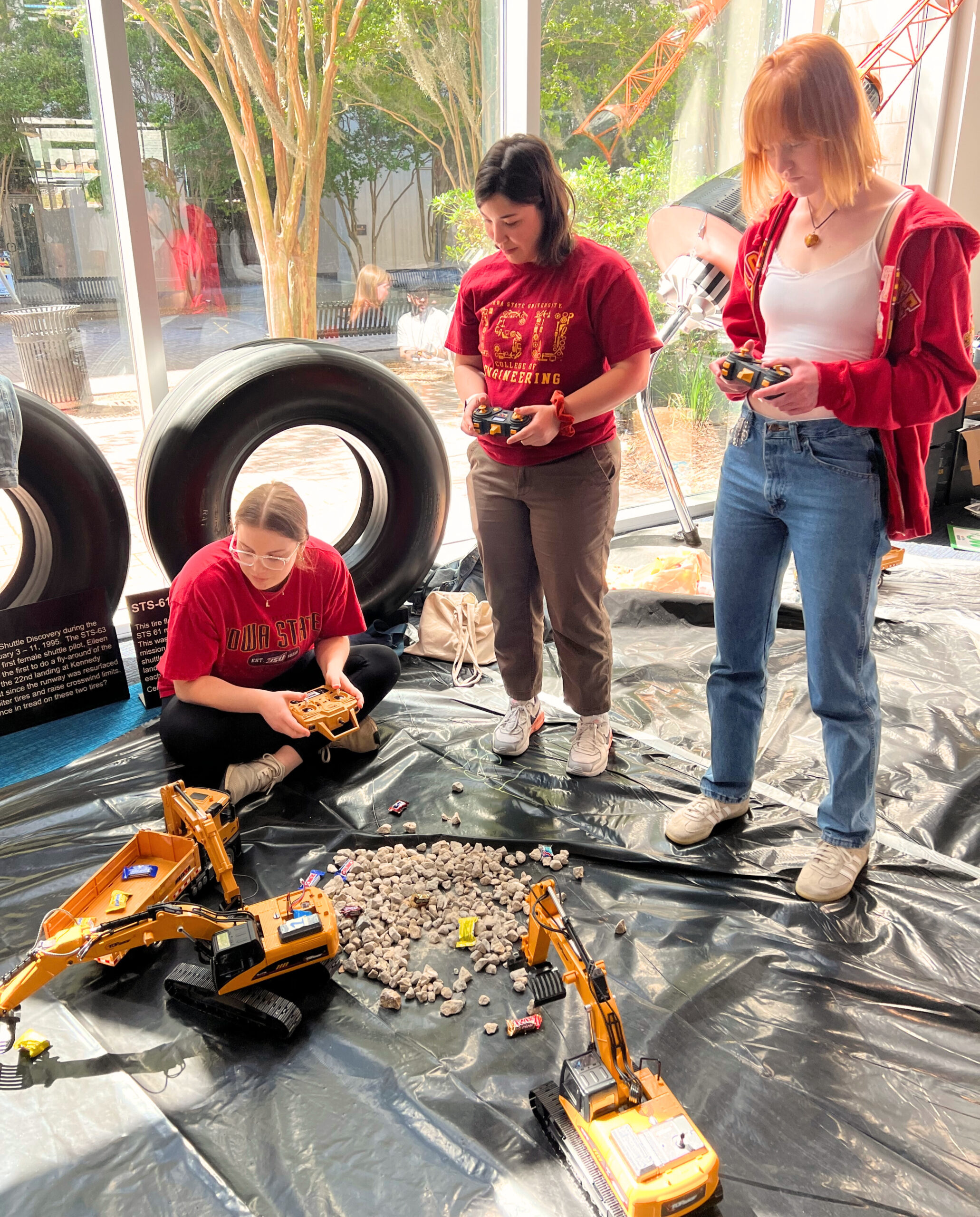 Three students manipulating excavators in competition