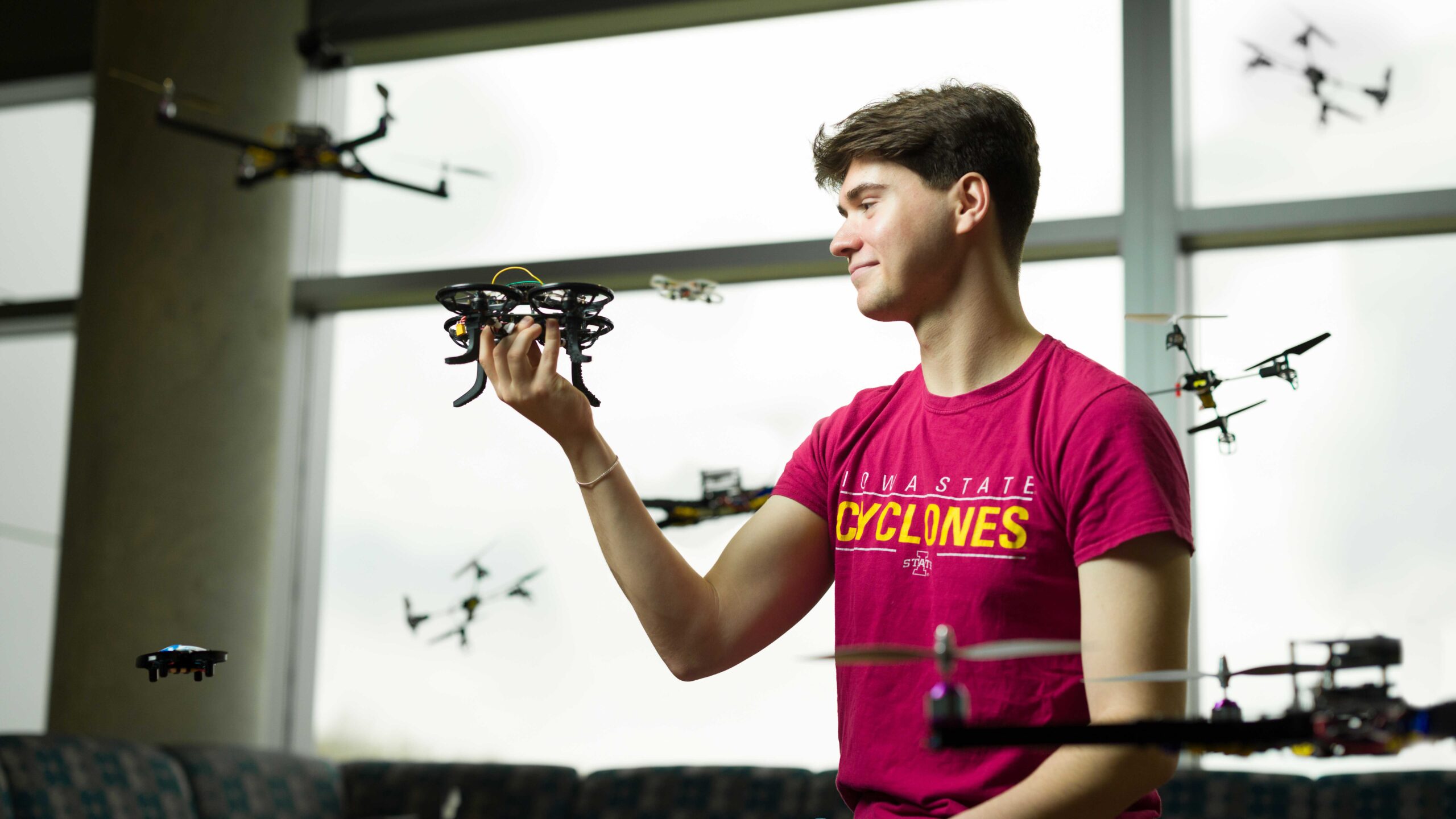 Trevor Friedl surrounded by drones as he is sitting on a chair.