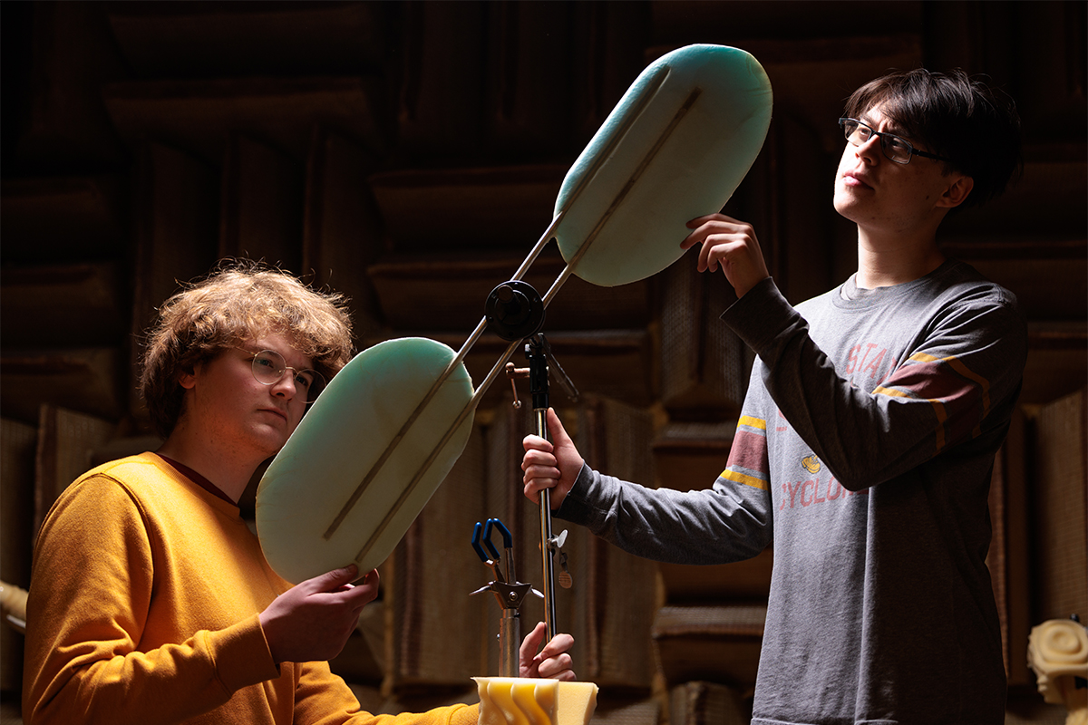 Students handling research equipment inside anechoic chamber