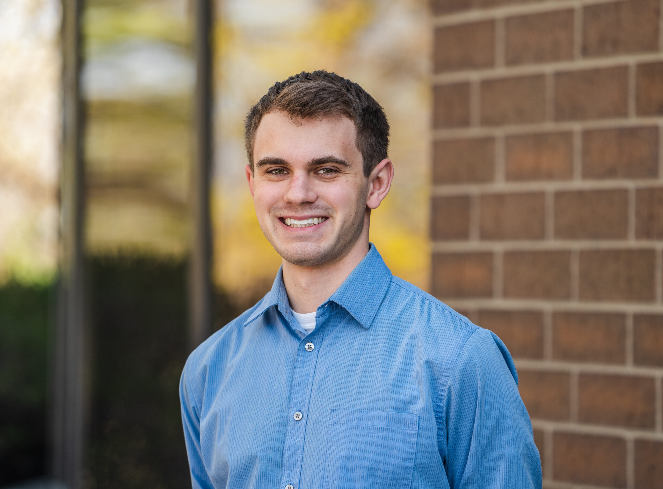 Brady Nahkala poses for headshot wearing a blue shirt. 