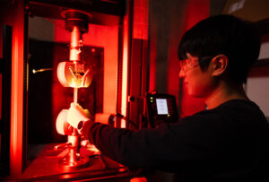 Student shown in Bastawros lab working with special machine emitting red light