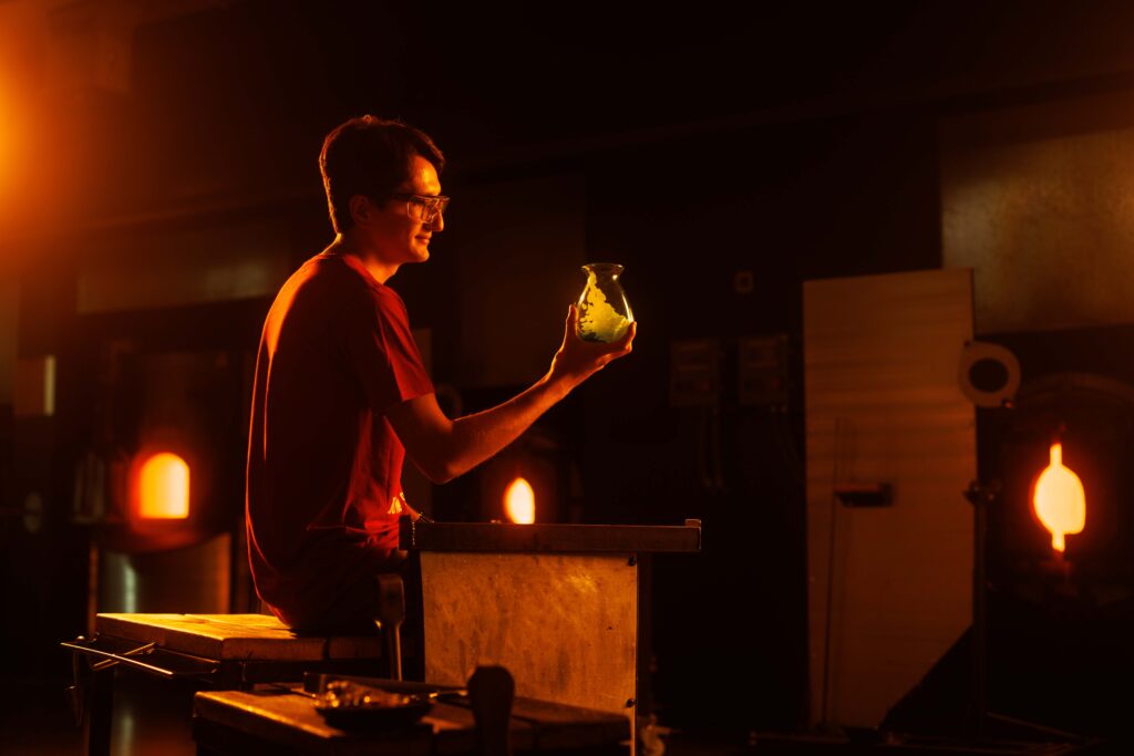 Student Nick Tader holds a vase in the Student Innovation Center glass blowing studio.