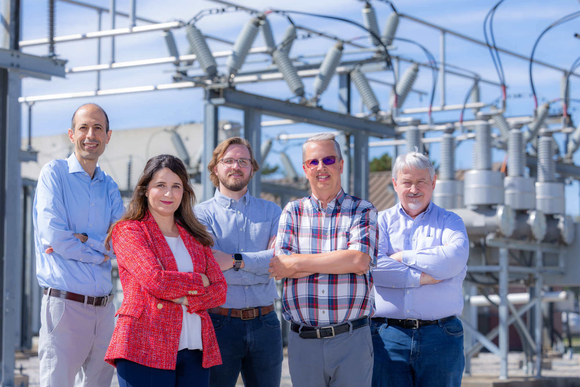 Team of professors posing in front of power plant.