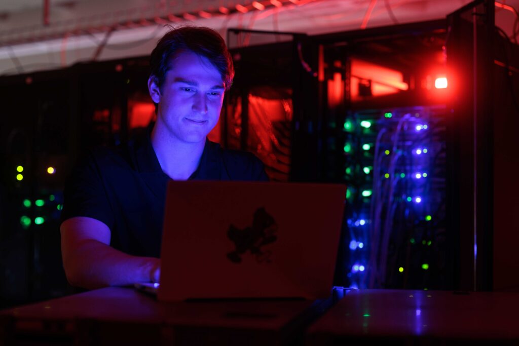 John Beuter sitting in front of his computer in the cyber security room. 