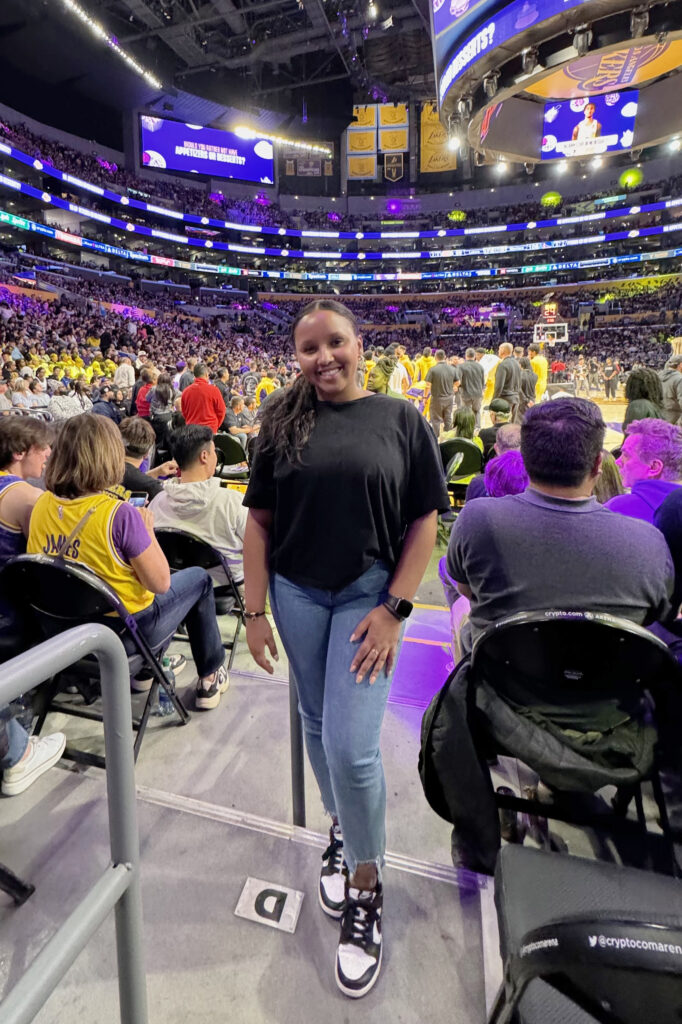 Macie VanNurden standing courtside at a LA Lakers basketball game.