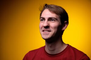 John Titus Barnett, outstanding senior in materials engineering, poses for a photo in front of a gold background.