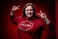 Bethany Groos, outstanding senior in biological systems engineering, holds up peace signs in front of a red background.