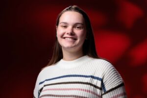 Vanessa Hupp, outstanding senior in chemical engineering, poses for a photo in front of a red background.