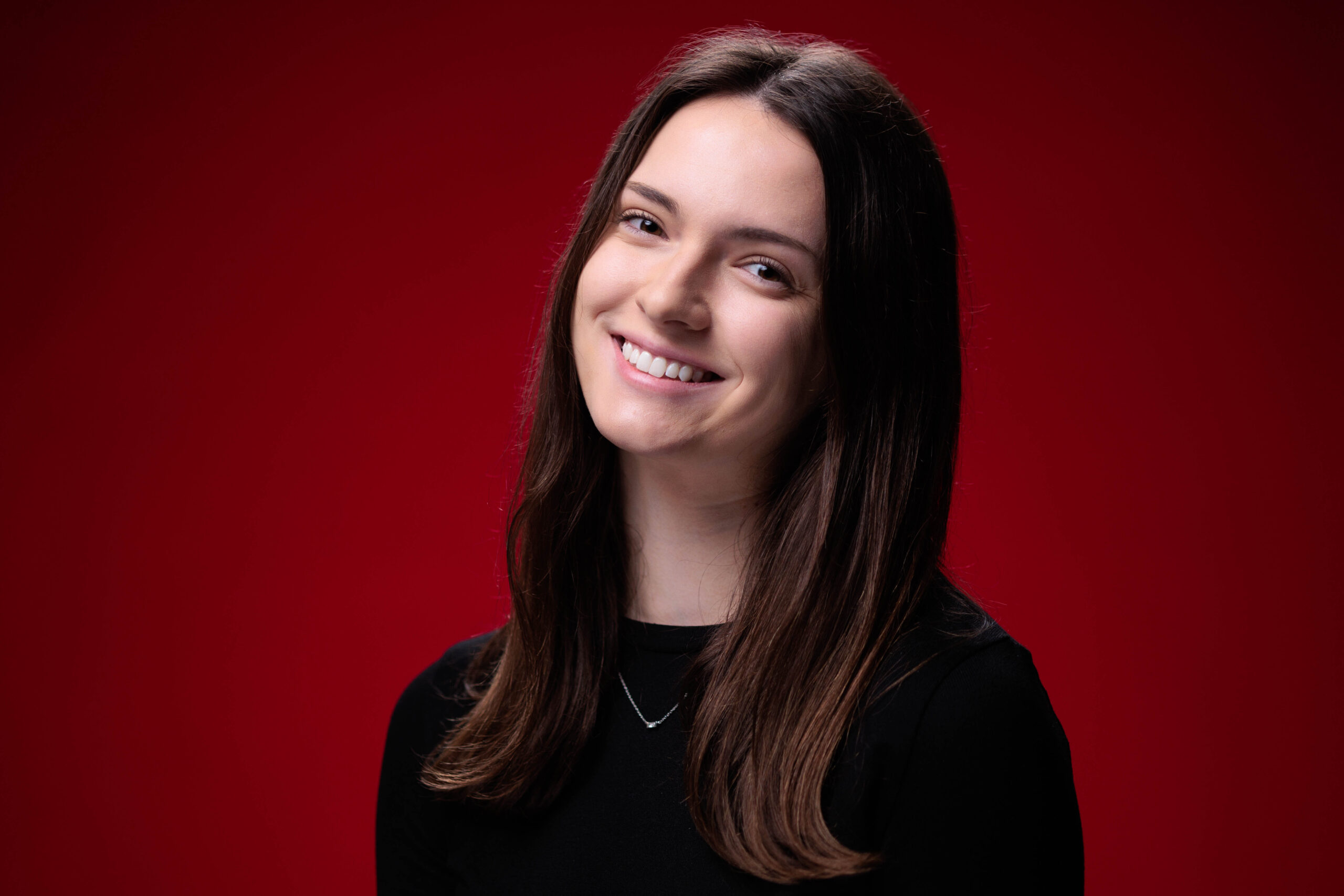 Kalista Leners, outstanding senior in mechanical engineering, poses for a photo in front of a red background.