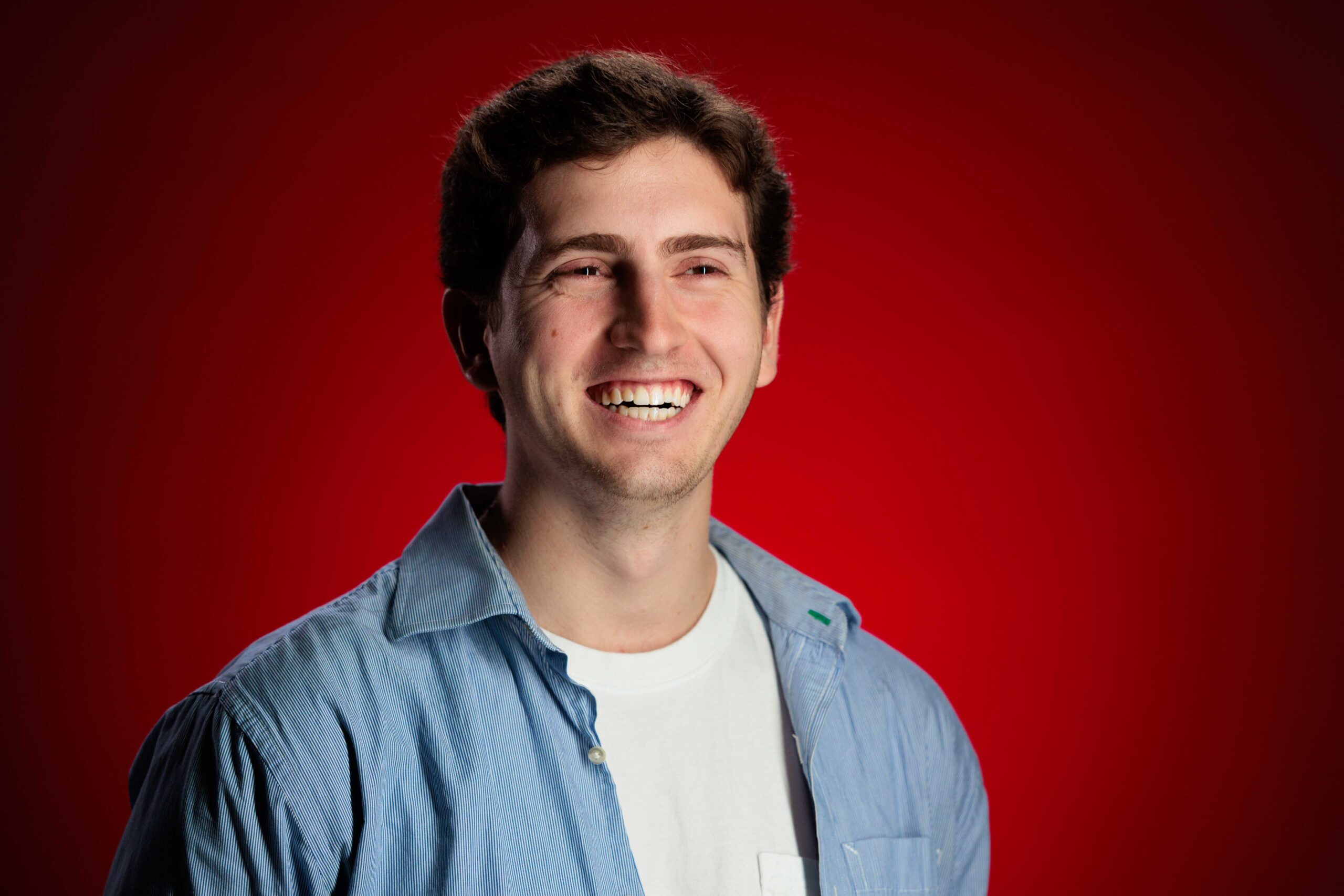 Mateo Rubel, outstanding senior in agricultural engineering, poses for a photo in front of a red background.