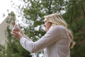 Lauren Spaete holding a beaker of water up, analyzing the contents in the sunlight.