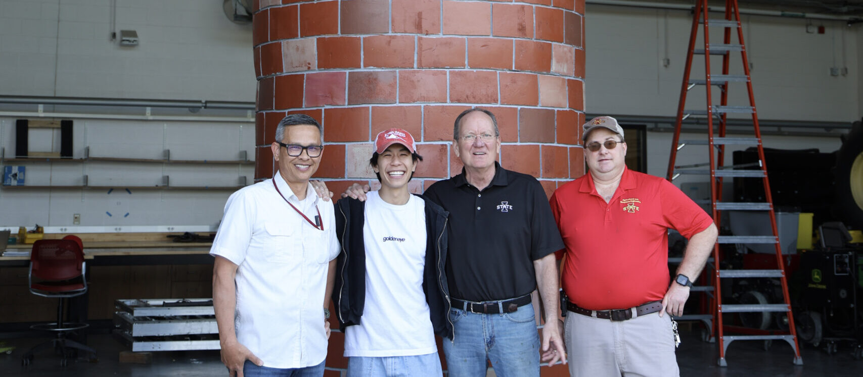 The Iowa State project team posing in front of the finished silo in their high-bay lab space. From left to right: Hoa Chi, Anthony Nguyen, Steve Bell, John Sheriff.