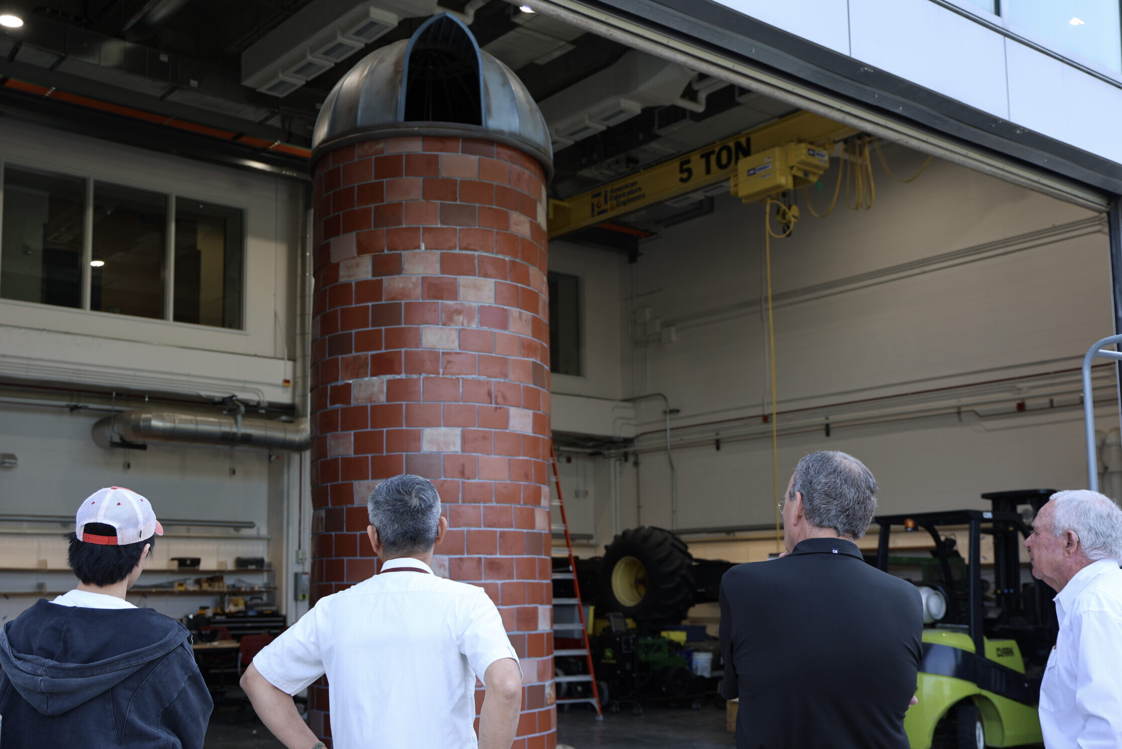 The project team is admiring the 20-foot standing glaze-tile silo from outside of the high-bay garage door.