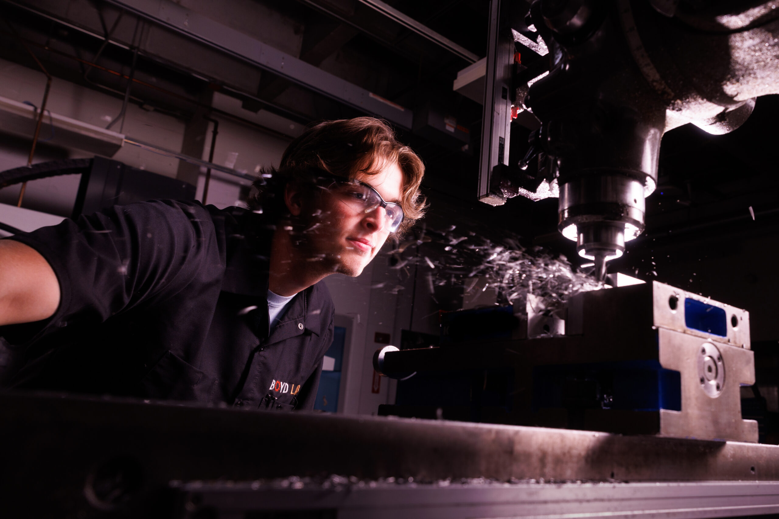Colin Livesay, a mechanical engineering student and technician in the Boyd Lab, leans in to make a cut using the lab's mill.