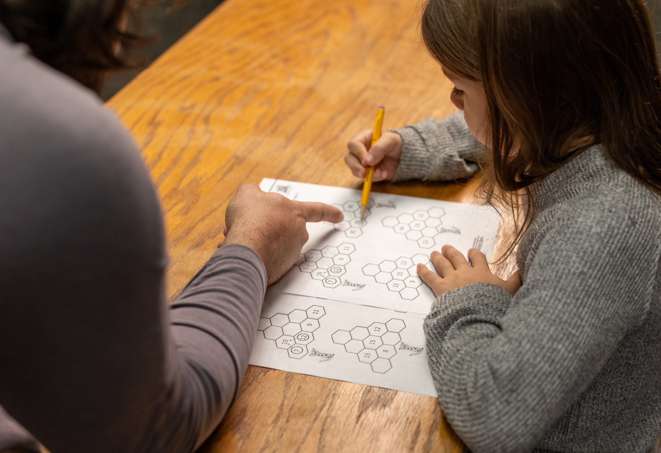 A student works on a math worksheet while a mentor helps.