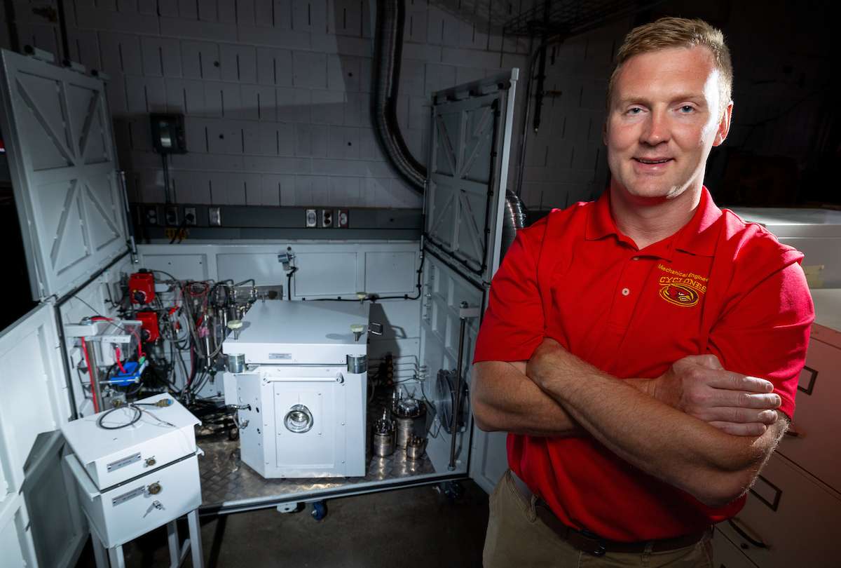 Todd Kingston stands in front of battery testing equipment in his lab.