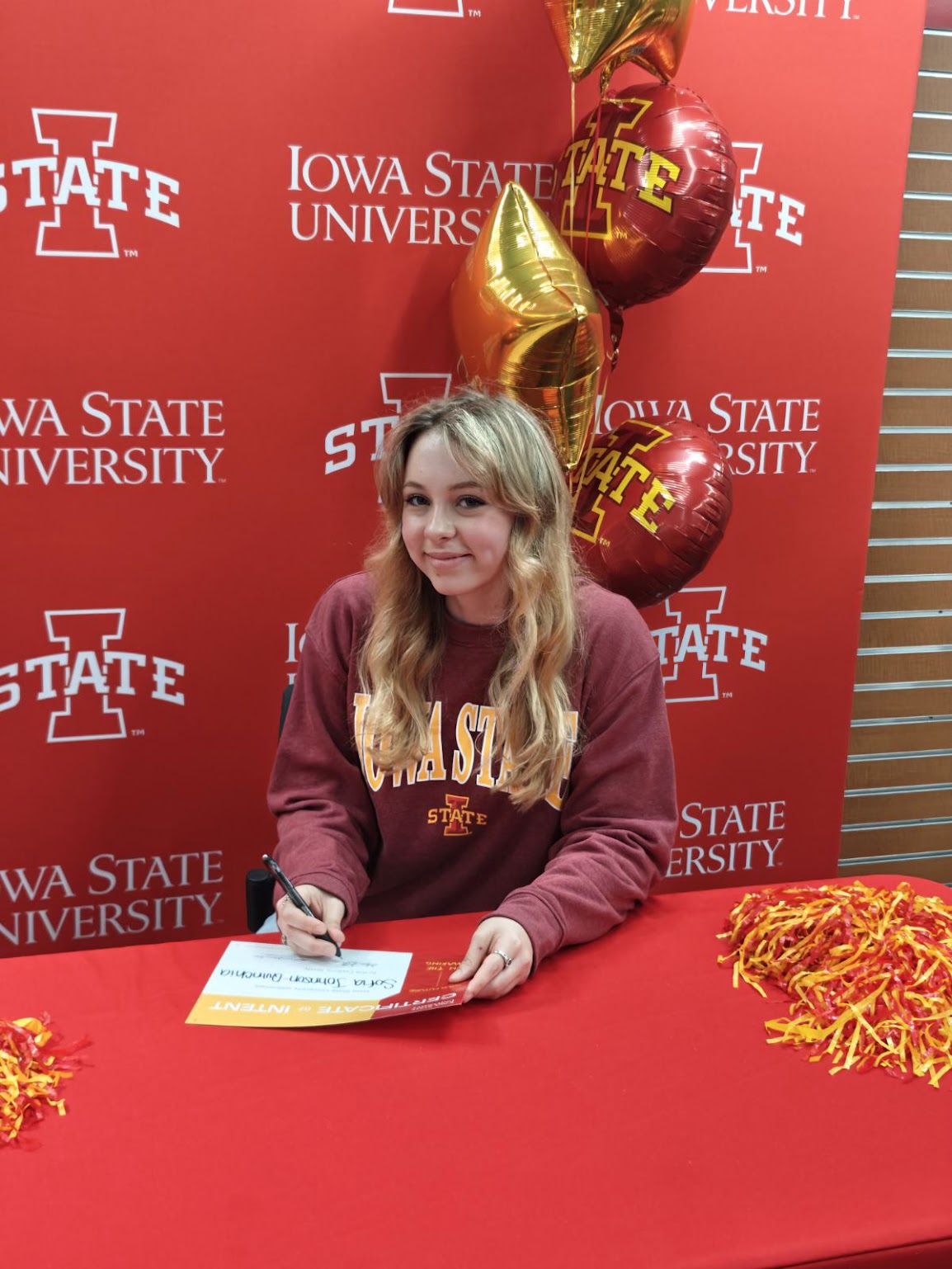 Sofia Johnson Quinchia poses at Iowa State University signing day wearing an Iowa State sweatshirt.