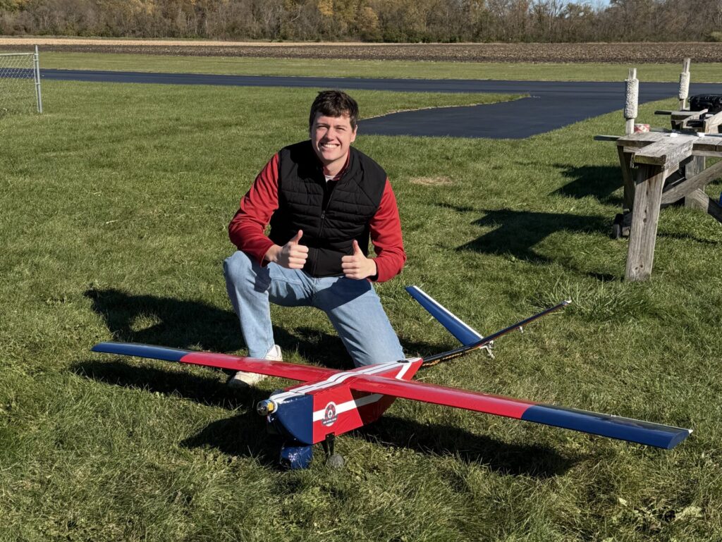 Sam Lanz gives thumbs up next to his senior design project plane.
